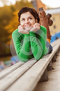 Pretty young woman lying on bench