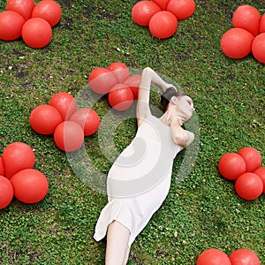 Pretty young woman lying down on grass. Fashion model