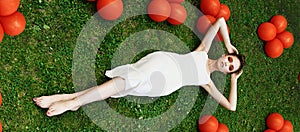 Pretty young woman lying down on grass. Fashion model