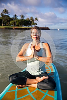 Pretty young woman in meditation on the water at Ala Moana state