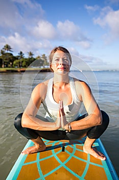 Pretty young woman in meditation on the water at Ala Moana state