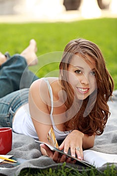 Pretty young woman model lying down reading