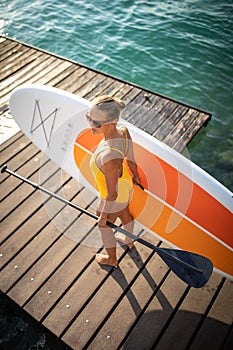 Pretty, young woman paddle boarding photo