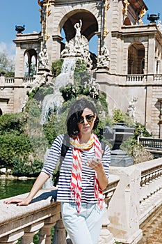 Pretty young woman with phone in front of the fountain