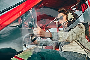 Pretty young woman pilot in headset ready to fly in small airplane