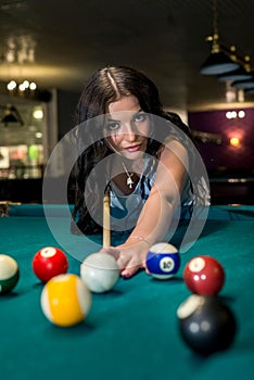 Pretty and young woman playing billiard in pub