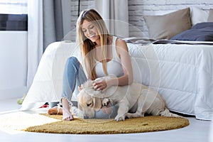 Pretty young woman playing with her dog while sitting on the floor at home