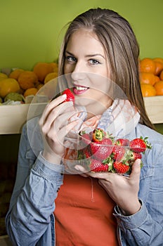 Pretty young woman posing while eating strawberries