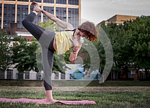 Pretty Young Woman Practicing Yoga in the Park