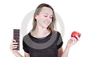 Pretty young woman with red apple and chocolate bar tempted  try to be healthy