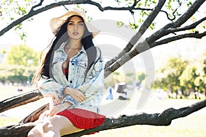 Pretty young woman in red dress smiling cheerful in green park at tree on summer sunny day, lifestyle people concept