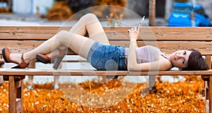 Pretty young woman relaxing lying on a park bench