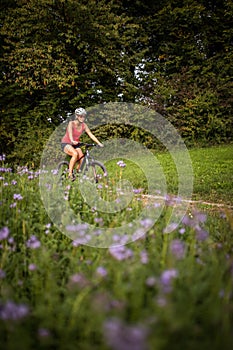 Pretty, young woman riding her mountain bike on a forest path