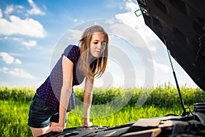 Pretty, young woman by the roadside after her car has broken down