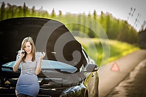 Pretty, young woman by the roadside after her car has broken down