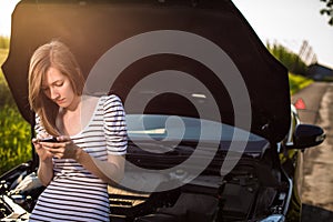 Pretty, young woman by the roadside after her car has broken down