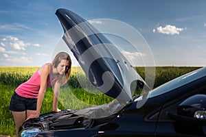 Pretty, young woman by the roadside after her car has broken down