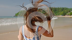 Pretty young woman running, flirting on tropical beach. Fitted girl smiling, playing with hair on the sea shore