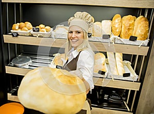 Pretty young woman selling bread in the bakery