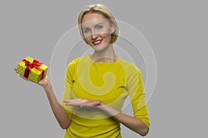 Pretty young woman showing gift box.