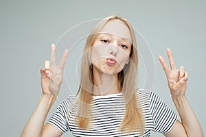 pretty young woman showing the peace sign on grey color background