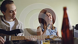 Pretty young woman is singing and her handsome friend guitarist is playing the electric guitar during rehearsal in nice