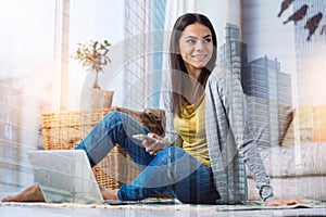 Pretty young woman sitting and holding a smart phone