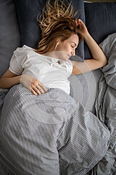 Pretty, young woman sleeping in her bed late in the morning