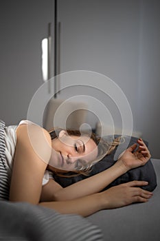 Pretty, young woman sleeping in her bed late in the morning on a weekend