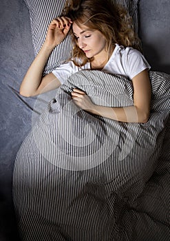 Pretty, young woman sleeping in her bed late in the morning on a weekend