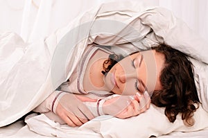 Pretty young woman sleeping on white bed