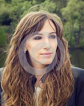 Pretty young woman with smokey eyes make up posing near river.