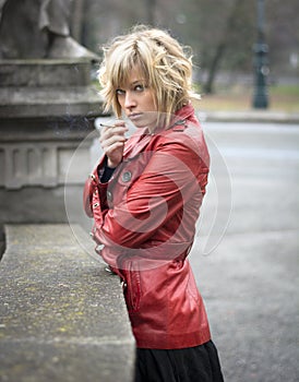 Pretty young woman smoking, wearing red leather jacket