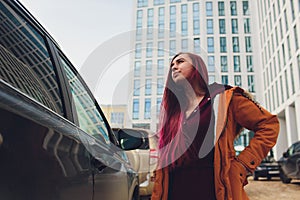 Pretty young woman standing and looking keys of car in her bag outdoors.