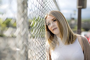 Pretty young woman standing near chain link fence