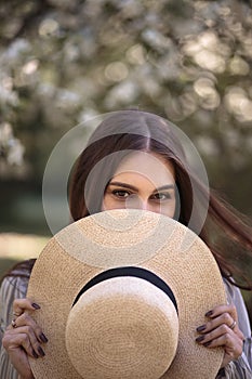 Pretty young woman in a summer garden, casual romantic style with hat