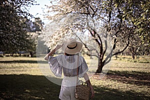 Pretty young woman in a summer garden, casual romantic style with hat