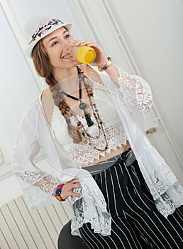 Pretty young woman with a summer hat drinks glass of orange juice