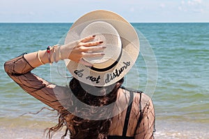Pretty young woman in summer vacation wearing straw hat enjoying the view at the ocean