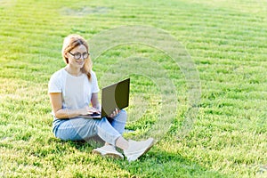 Pretty young woman surfing internet on laptop outdoors