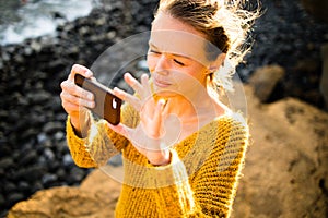 Pretty, young woman taking photos with her smartphone
