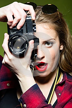 Pretty young woman taking photos with a retro camera.