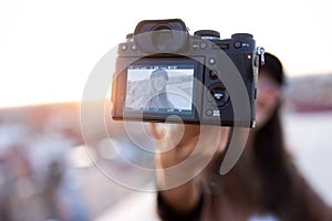 Pretty young woman taking a selfie with camera while sitting on the rooftop