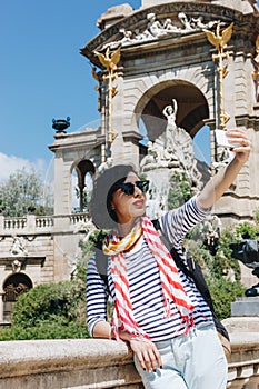 Pretty young woman taking selfie in front of the fountain