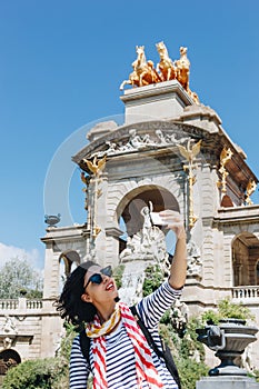 Pretty young woman taking selfie in front of the fountain