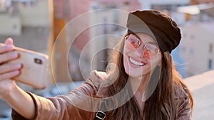 Pretty young woman taking a selfie while sitting on the rooftop.