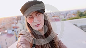 Pretty young woman taking a selfie while sitting on the rooftop.