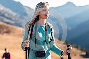 Pretty young woman traveler with backpack looking to the side while walking on mountain