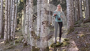 Pretty young woman traveler with backpack looking to the side while walking in the natural forest.