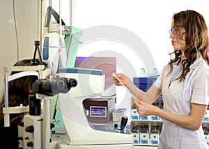 Pretty young woman undergone an ocular fundus inspection with ophthalmologist optometrist optician photo